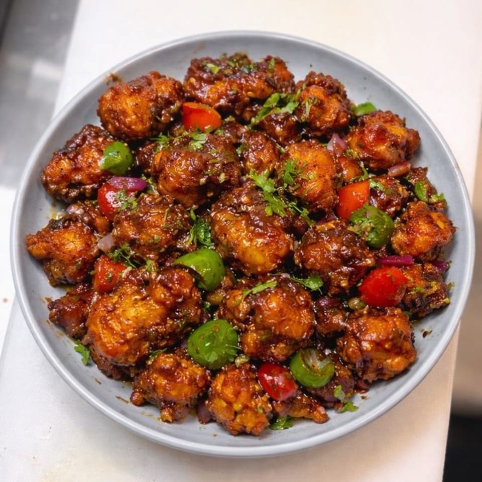 A plate of Garam Mirchi's Indo-Chinese Gobi Manchurian, garnished with bell peppers and cilantro.