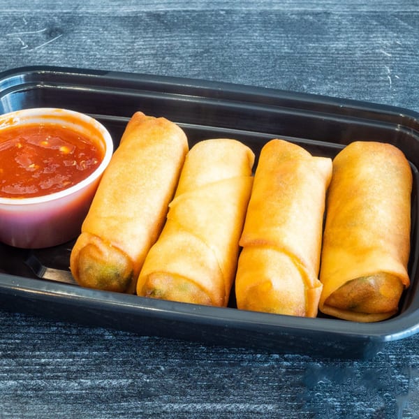 Four golden-brown spring rolls and a cup of red dipping sauce in a black container.